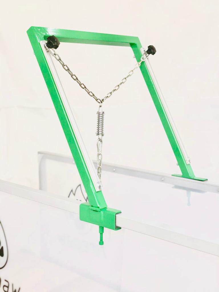 A close-up of the FirePaw dog treadmill attachment system, featuring a green metal frame with an adjustable chain and spring mechanism for secure harness connection.