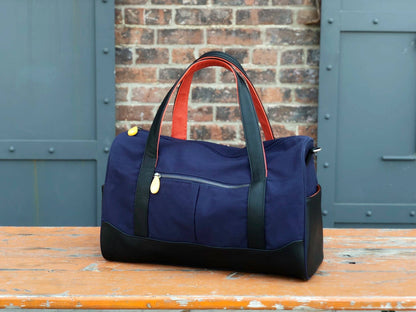Canopy Verde Dekalb navy vegan leather gym and travel duffle bag placed on a wooden bench in an urban setting