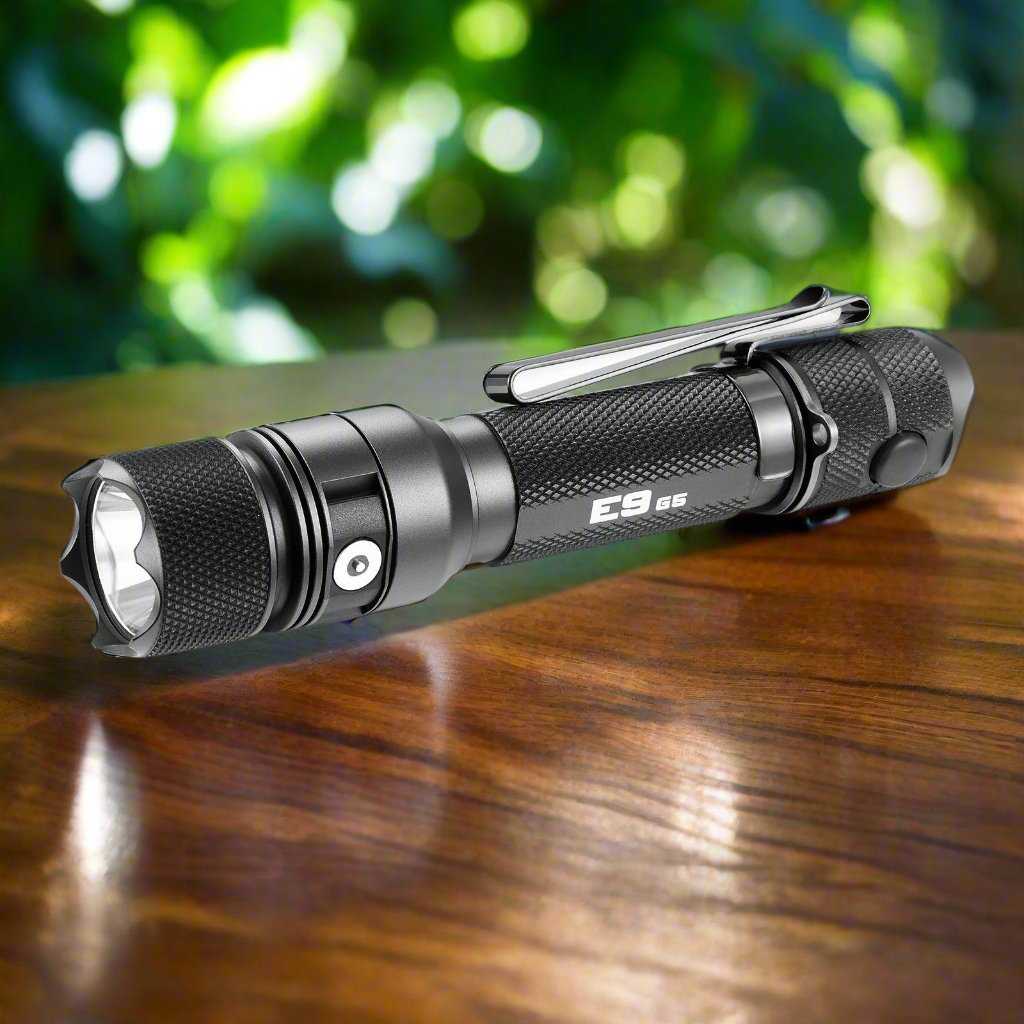 Powertac E9 GEN5 tactical flashlight in black aluminum, compact 3000 lumen rechargeable EDC torch on a wooden surface