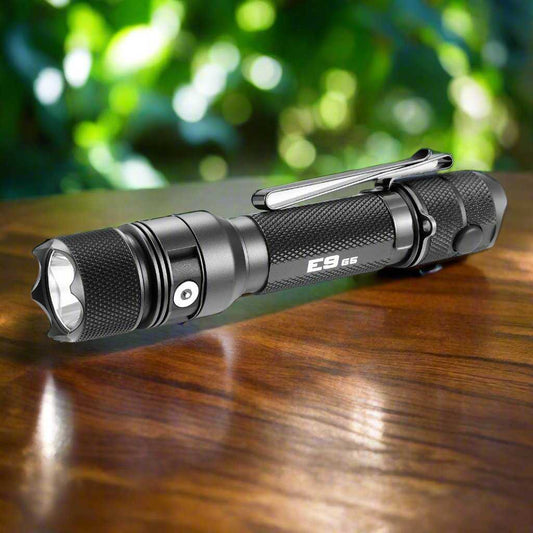 Powertac E9 GEN5 tactical flashlight in black aluminum, compact 3000 lumen rechargeable EDC torch on a wooden surface