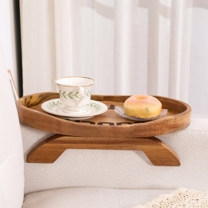 Wooden sofa arm tray used as a small table holding coffee and snacks in a cozy living room