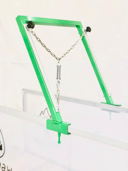 A close-up of the FirePaw dog treadmill attachment system, featuring a green metal frame with an adjustable chain and spring mechanism for secure harness connection.