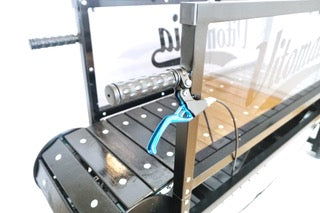 A close-up detail of the FirePaw dog treadmill safety brake system, featuring a blue hand lever on a black handlebar next to the mechanical running track.