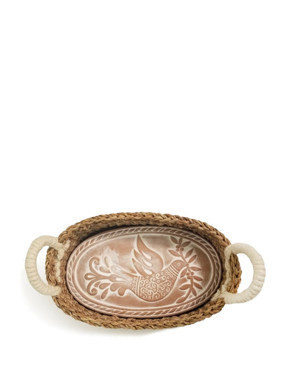 Terracotta bread warming stone with bird engraving resting inside a handwoven seagrass basket.