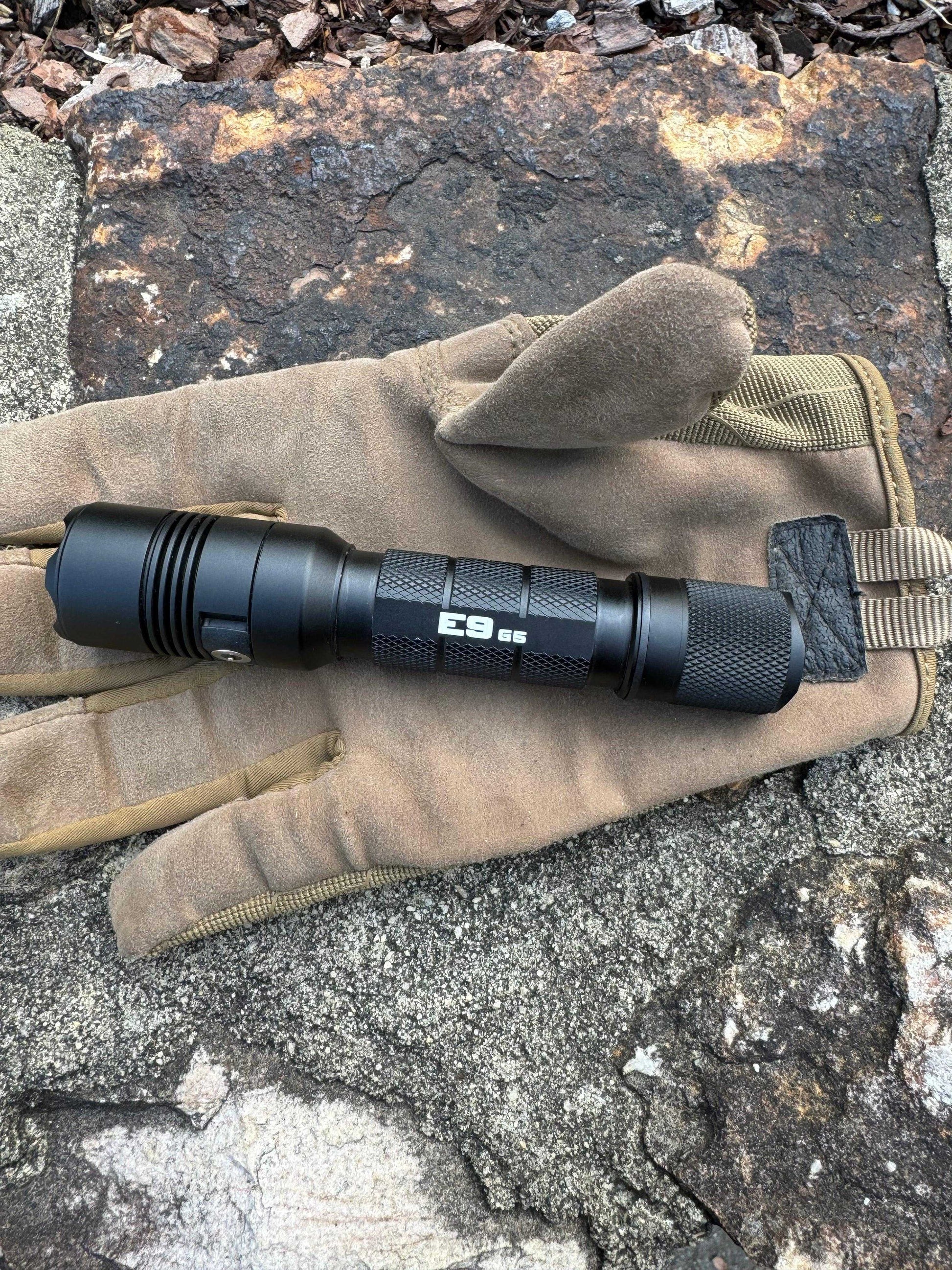 Tactical flashlight placed on rock outdoors, designed for camping and field use