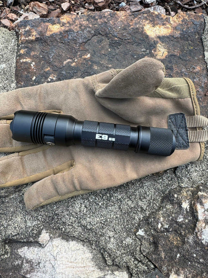 Tactical flashlight placed on rock outdoors, designed for camping and field use
