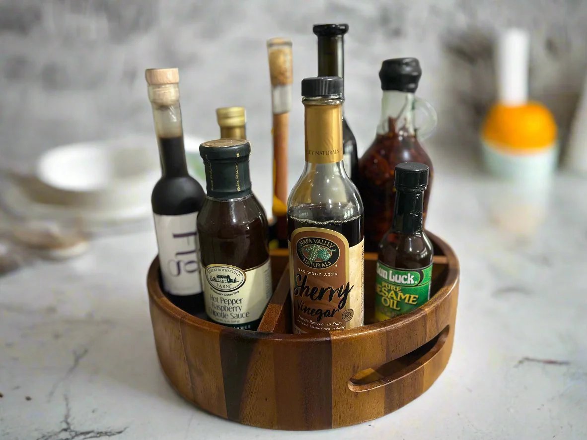 Acacia wood Lazy Susan organizer holding oil and vinegar bottles on a kitchen counter